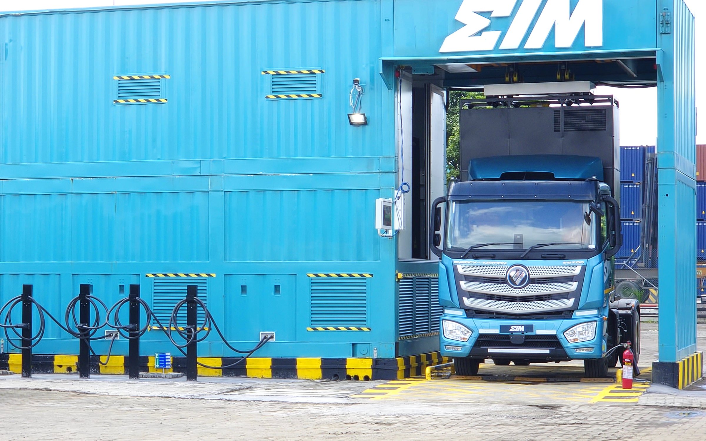 Two EIM electric tractors at the JNPT battery swapping and charging station, one inside the swap bay under the EIM sign