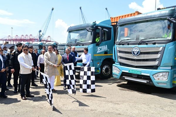 Officials wave chequered flags in front of a line of EIM electric trucks at JNPA